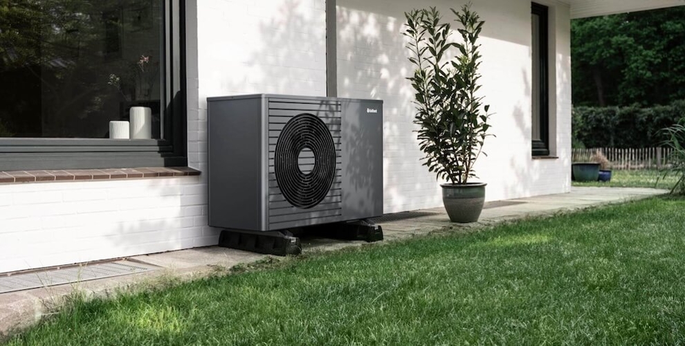 Wärmepumpe vor einem Haus im Gras