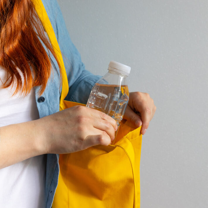 Frau verstaut Plastikflasche in Tragetasche