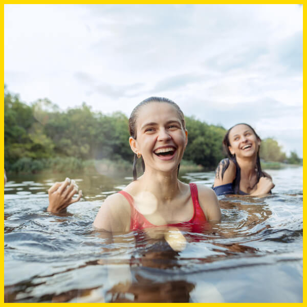 Gruppe junger Frauen springt ins Wasser zur Abkühlung.