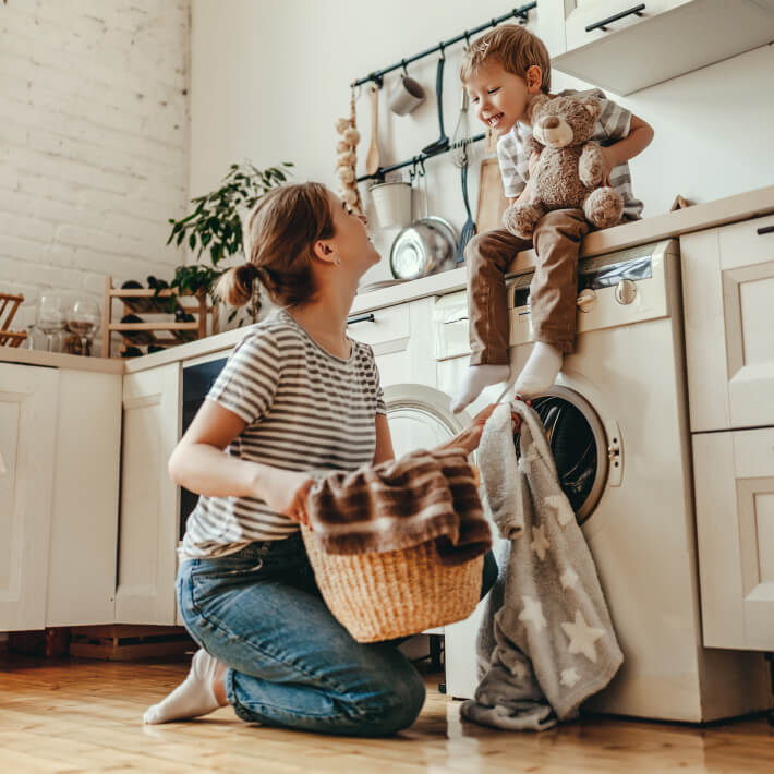Frau mit Kind vor Waschmaschine