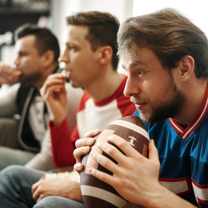 Drei Männer schauen den Superbowl im Fernseher an