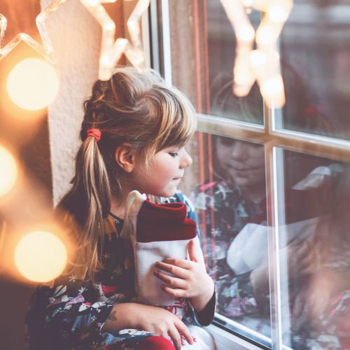 Kind sitzt am verschneiten Fenster