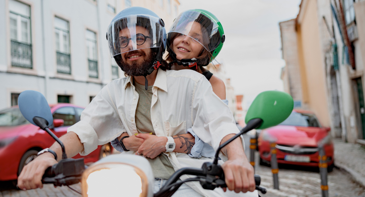 Zwei Personen gemeinsam auf dem E-Roller fahrend