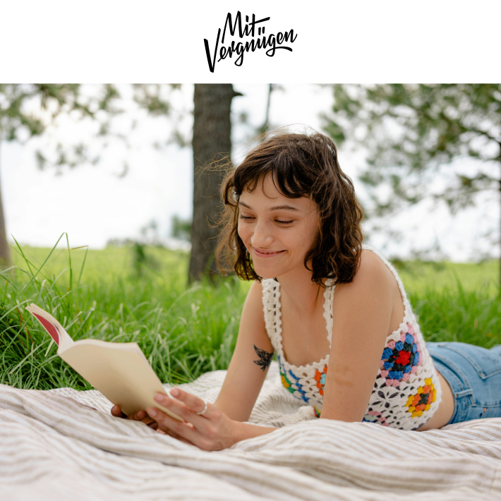 Junge Frau mit Buch auf Picnicdecke